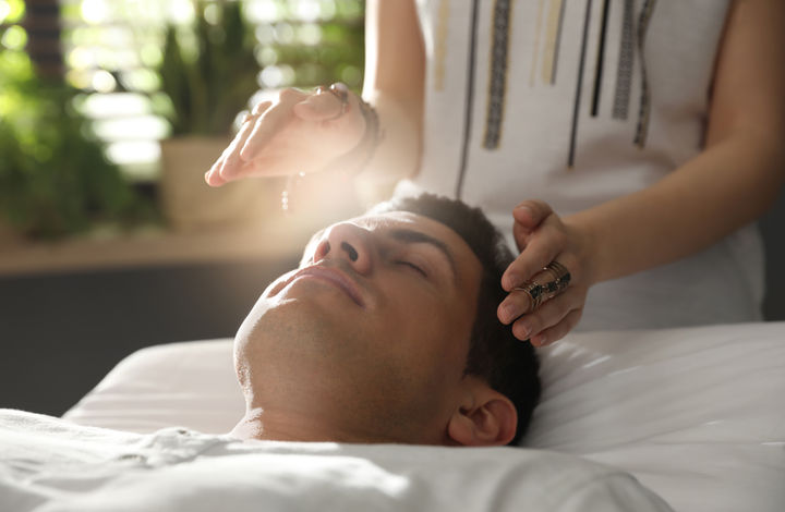 Energy healing session with hands held around the head